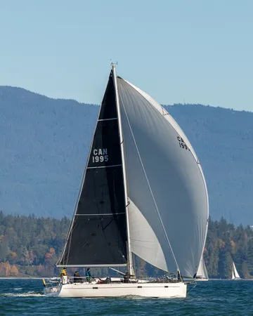 Off Piste, sail number CAN 1995, running under a white spinnaker past Stanley Park.